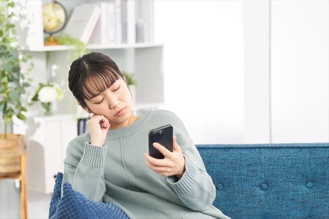 スマホを見ながら考え込む女性